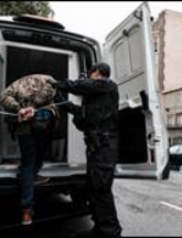 Image of suspect being placed into police vehicle