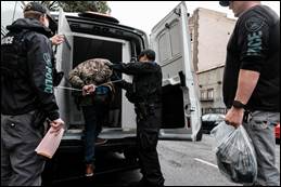 Image of suspect being placed into police vehicle