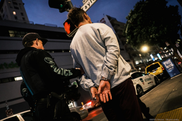 Suspect being led in handcuffs by officer