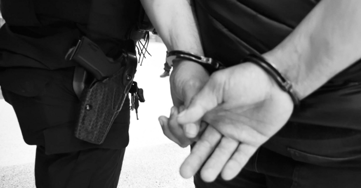 Image of suspect in handcuffs being escorted by officer close-up