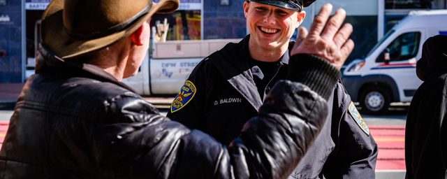 SFPD officer smiling at man wearing cowboy hat